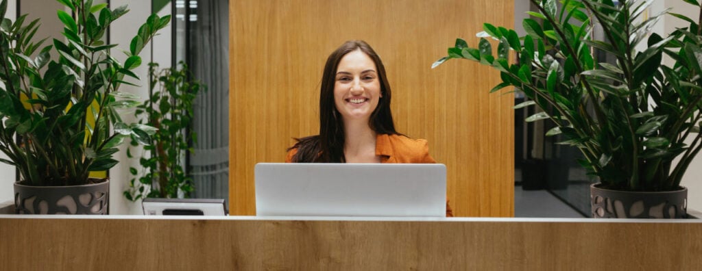 Woman Smiling Behind a Hotel Lobby Checkin Desk.