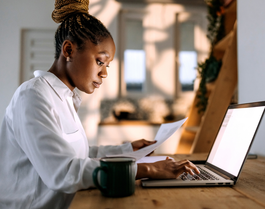 A woman sitting at a table with a laptop, working on her computer.