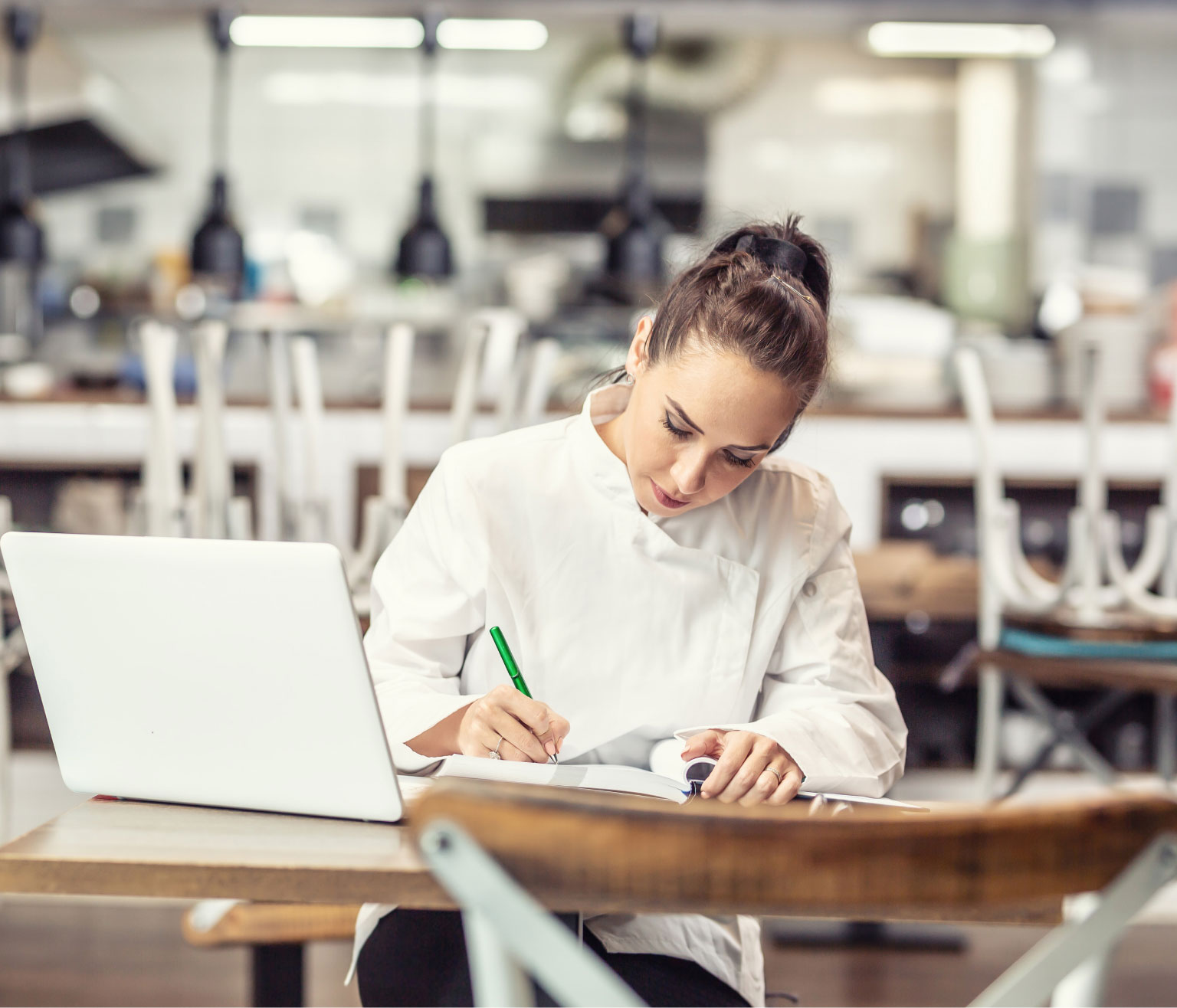 Chef working to manually reconcile spreadsheets at a desk in front of a computer.