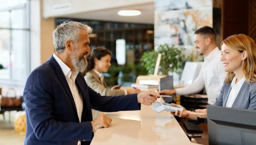 Hotel manager greeting a guest at check-in, showcasing a welcoming atmosphere with a focus on seamless hotel payment processing with credit card analytics.